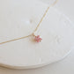 Necklace with a pink gemstone on a white stone surface
