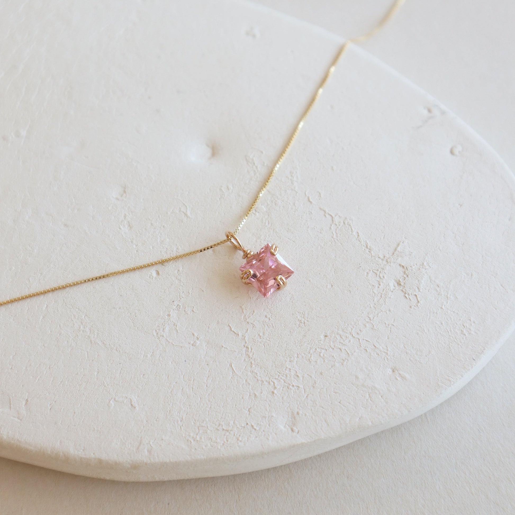 Necklace with a pink gemstone on a white stone surface