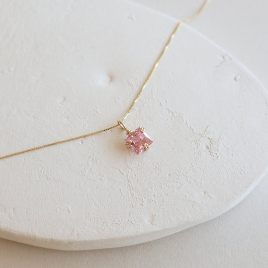 Necklace with a pink gemstone on a white stone surface